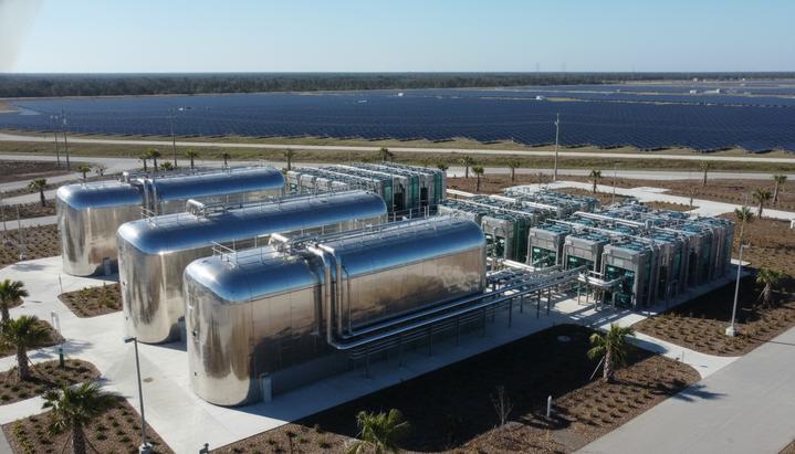 Современная установка по производству зеленого водорода: резервуары для хранения и трубопроводы на фоне солнечной электростанции.